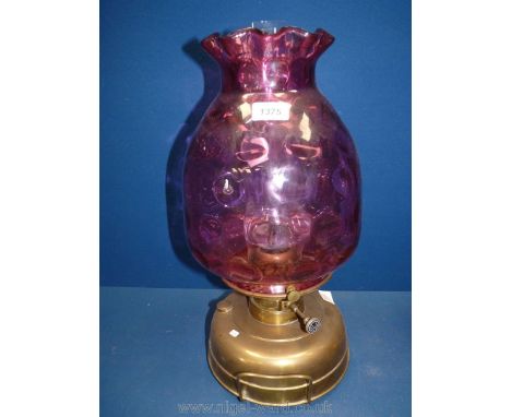 A church heater/lamp on brass bass, standing on three feet with a 6" diameter gallery supporting a large cranberry glass glob