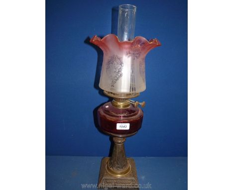 An Oil Lamp with pink to white ombre fluted shade with etched floral decoration, cranberry reservoir, on metal stand, complet