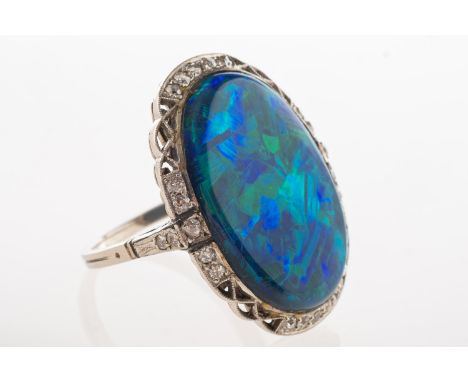 A black opal and diamond ring, an oval-cut black opal cabochon, measuring approx. 24mm x 16mm, with 'chaff' pattern, showing 