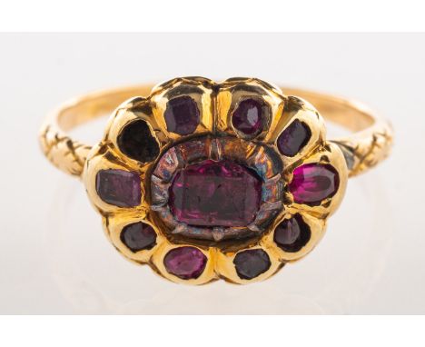 A Georgian ruby ring, an enclosed back flowerhead designed ring set with mixed-cut rubies (one missing), engraved shoulders (