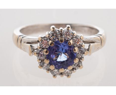 A tanzanite and diamond ring, of cluster design and set with a circular-cut tanzanite with a surround of brilliant-cut diamon