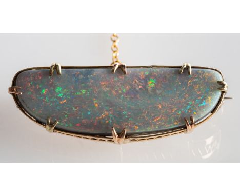 An opal brooch, set with an elongated white oval opal cabochon in a claw & basket setting, pin, safety catch and safety chain