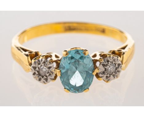 A three stone ring, set to the centre with an oval-cut blue stone with a single-cut diamond set to each side in an illusion s