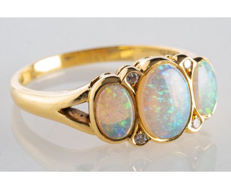 An 18ct gold opal & diamond ring, set with three oval-cut opal cabochons and four brilliant-cut diamonds, UK hallmark, size O