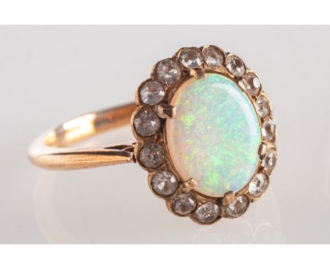 An antique opal cluster ring, set to the centre with an oval opal cabochon with a surrounded of small white sapphires, unmark