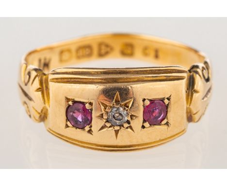 An 18ct gold Edwardian ring, star set with an old-cut diamond and two circular-cut red stones, scroll engraved shoulders, UK 