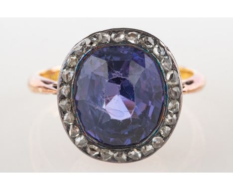 An antique purple sapphire and diamond ring, with an ornate foliate carved gallery and set to the centre with an oval-cut pur