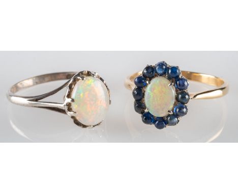 A group of two opal rings, including a cluster ring set to the centre with an oval opal cabochon surrounded by circular-cut s