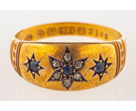 A 15ct gold Edwardian ring, star set with three circular-cut synthetic sapphires, the centre stone having a surround of rose-