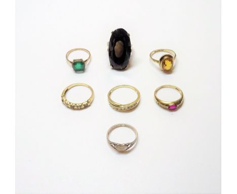 A 9ct gold ring, claw set with an oval cut smoky quartz, a 9ct gold, sapphire and diamond set five stone ring, a 9ct gold rin