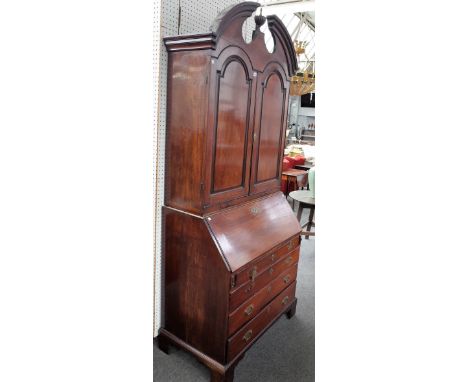 A mid-18th century mahogany bureau cabinet, the broken arch top cornice, over a pair of panelled doors, the fall with fitted 