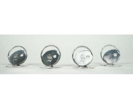 A set of four silver menu holders, formed as artists palettes, each initial engraved and raised on circular disc stands, by W