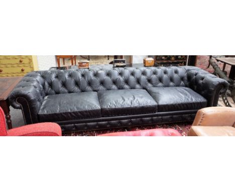 A large studded black leather upholstered button back Chesterfield sofa, on turned supports, 300cm wide x 78cm high.