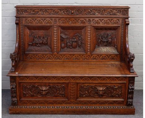 A 19th century carved oak box seat settle, with carved triple panel back and downswept winged beast arm supports, 138cm wide 