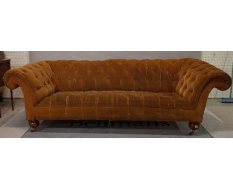 A late Victorian mahogany framed Chesterfield sofa, with roll over arms and brown button back upholstery on ball supports, 22
