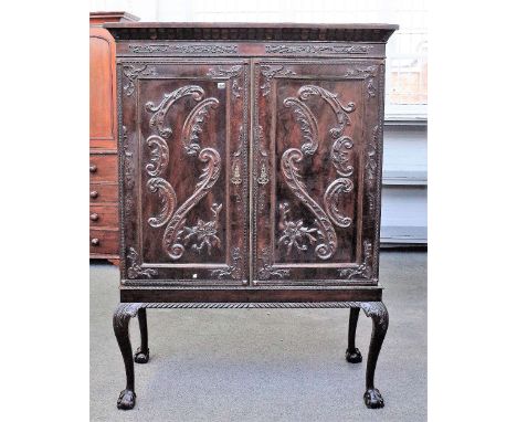  A mahogany linen press on stand, the moulded cornice over a pair of carved panel doors, resting on four ball and claw feet, 