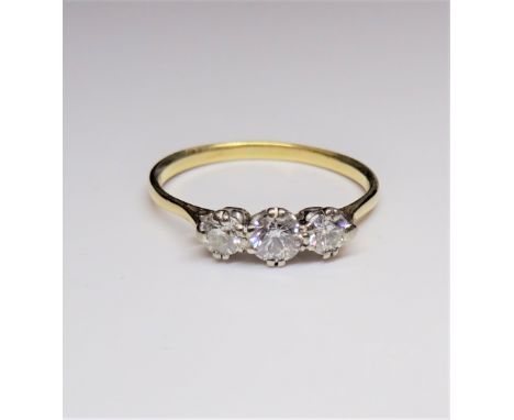A gold and diamond set three stone ring, claw set with a row of circular cut diamonds and with the principal diamond mounted 