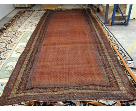 A Saraband long carpet, Persian, the madder field with an allover boteh design, various narrow borders, 584cm x 237cm. 