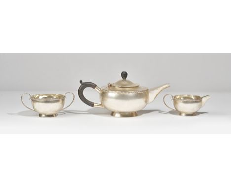 Silver tea wares, comprising; a teapot of squat circular form, having black fittings, Birmingham 1931, a twin handled sugar b