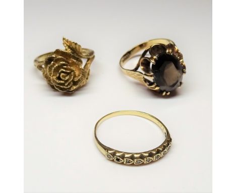 A 9ct gold ring, claw set with an oval cut smoky quartz, ring size S, a 9ct gold ring, designed as a flower, ring size O and 