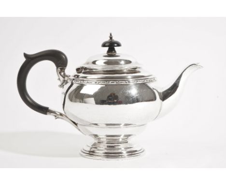 A silver teapot, of shaped circular form, having a decorated rim, with a black composition handle and finial to the hinged li