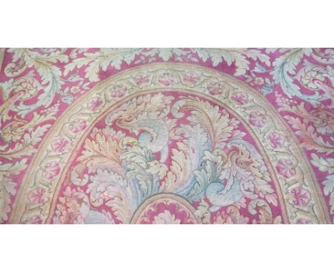 A Savonnerie carpet, French, the red field with a central oval, surrounded by bold leaf sprays, an outer circular frame, 520c