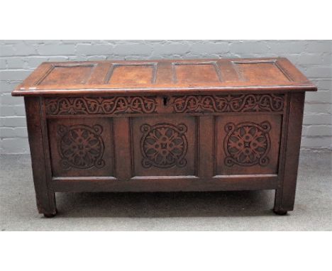 A 17th century oak coffer, with four panel lid and carved triple panel front, 140cm wide x 73cm high.