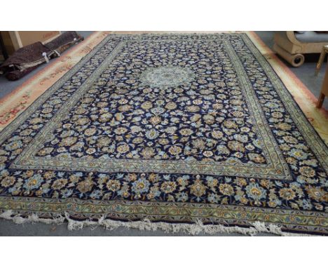 A Kashan carpet, Persian, the indigo field with a pale indigo roundel, a complementary indigo border, 494cm x 305cm. 