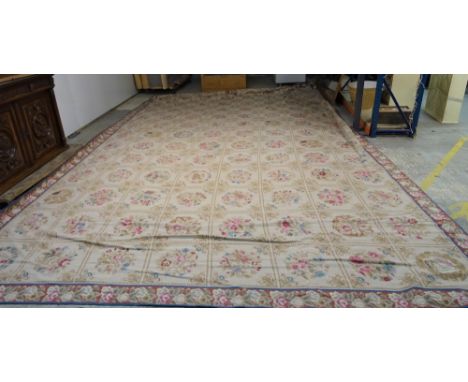 A needlework carpet, the cream ground with a series of flower motifs in a grid design, enclosed by a madder floral border, 73