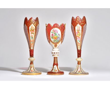 A pair of late 19th century Bohemian ruby glass vases with foliate painted white enamel overlay against a tapering body with 