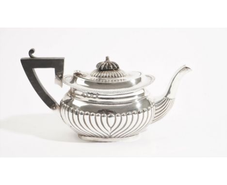 A silver teapot, of oval form, with curved fluted decoration, fitted with a black handle and finial to the hinged lid, Birmin