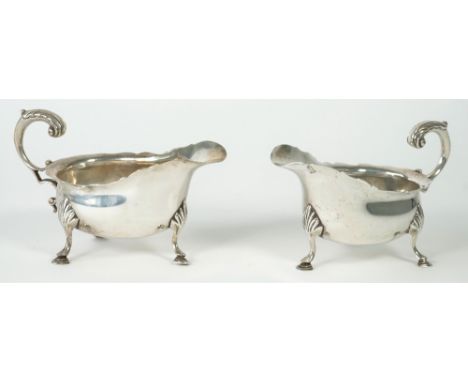 A pair of silver sauceboats, each with a scrolled handle, a shaped rim and raised on three feet, London 1903, combined weight
