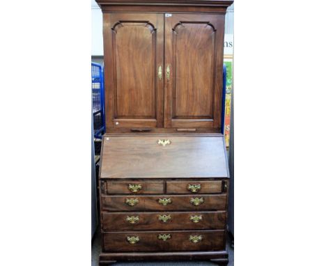 A mid-18th century mahogany bureau cabinet, the pair of panel doors over a fitted interior, two short and three long graduate