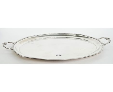 A silver shaped oval twin handled tray, having cast motifs to the handles and with a reeded rim, Sheffield 1975, length 60cm,