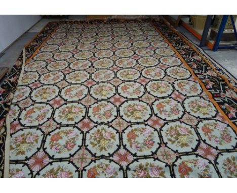 A large needlework carpet, decorated with floral octagons, enclosed by a black bird border, modern, 691cm x 391cm. 