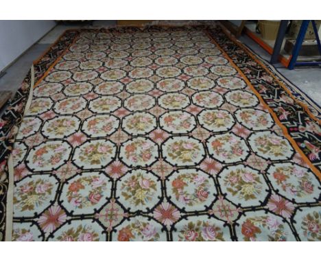 A large needlework carpet, decorated with floral octagons, enclosed by a black bird border, modern, 691cm x 391cm. 