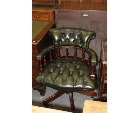 A Reproduction button back green leather and mahogany revolving captains chair the padded arm rest supported on baluster shap