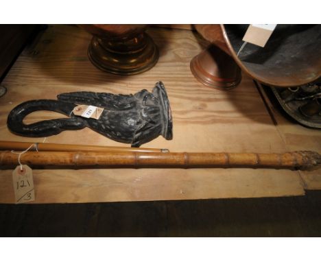 A Victorian painted iron swan figural doorstop , a three sectional cane with white metal mounts and a second walking stick.(3