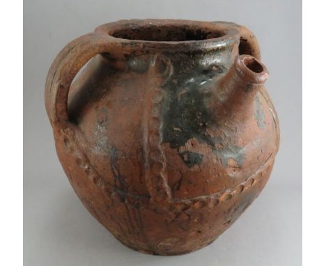 A large and impressive medieval earthenware three-handled vessel with pouring spout, c. 1500. It has simple applied and geome