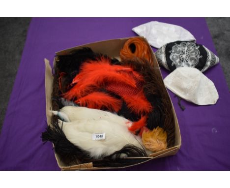 A box full of vintage and antique millinery feathers and similar items.