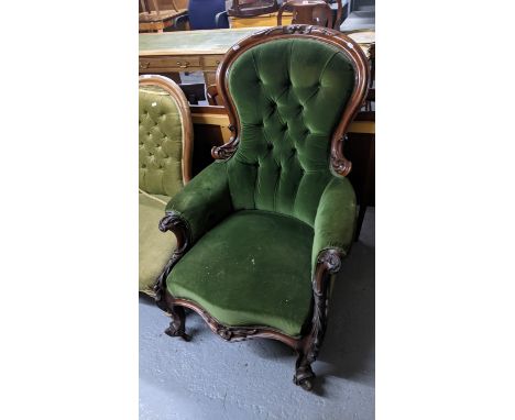 A Victorian carved mahogany upholstered armchair with scrolled leaf relief decoration, button back upholstered in green dralo