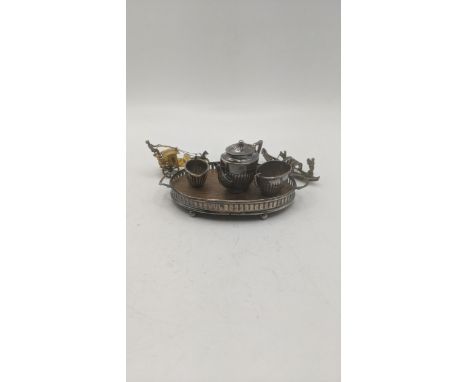 A silver miniature three-piece tea service to include a teapot, sugar bowl, milk jug, and silver pierced and wooden twin hand