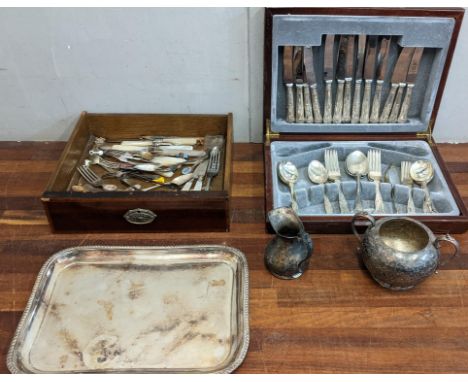 A collection of silver plated items to include a boxed canteen of cutlery, mixed flatware, and souvenir spoons, a tea tray, a