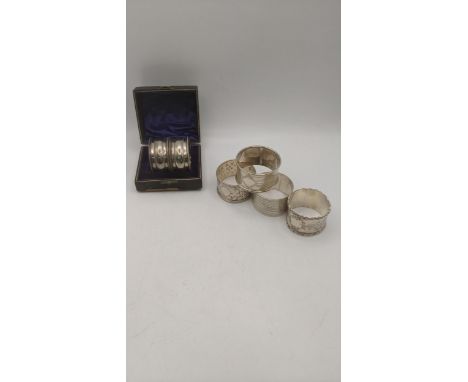 Six silver napkin rings to include a pair in a fitted case, a floral embossed example, two engraved examples and one with an 