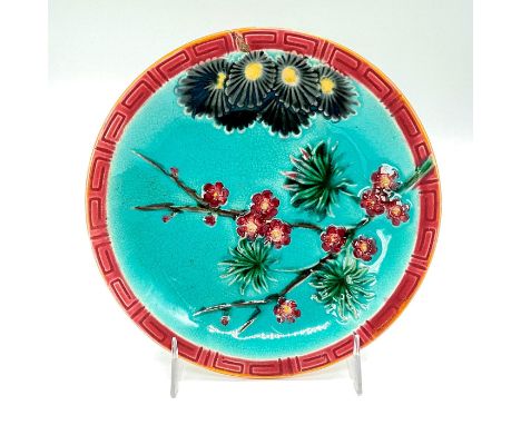 Ceramic plate with blue background, crimson Greek key impressed border pattern, and blossoming tree branches.Wedgwood impress