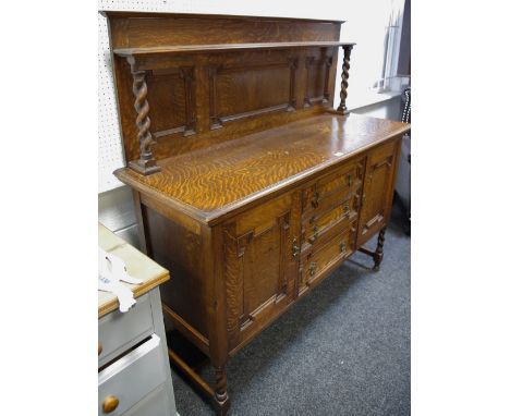 An oak sideboard, shelf  and barley twist supports to panelled gallery, oversailing top, three graduated drawers flanked by p