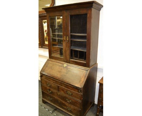 A George III oak bureau bookcase, outswept cornice over two glazed doors, fall front enclosing stepped interior, sliding plat