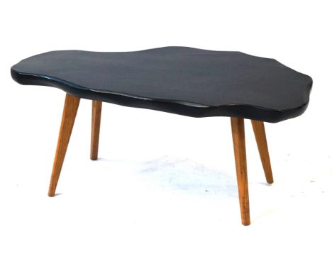 Post War elm coffee table of shaped oval formHaving a black painted top above four light elm splayed legs, length 85cm.