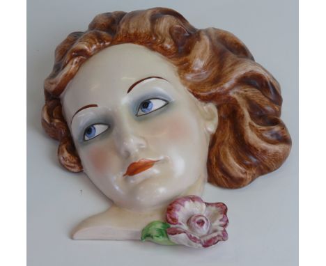 A Goebel Art Deco ceramic wall maskModelled in the form of a girl with sweeping brown hair and a flower beside her neck, impr