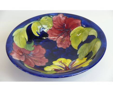 A Walter Moorcroft pottery circular bowlDecorated in the Hibiscus pattern on a blue ground, printed factory marks and dated 1